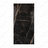 Black Daytona porcelain slab displayed on easel against luxury marble backdrop showing dramatic gold and white veining for UAE interior design
