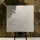 Close-up of Resina Grey matte porcelain tile showing detailed travertine texture, natural cracks, and 9mm thickness